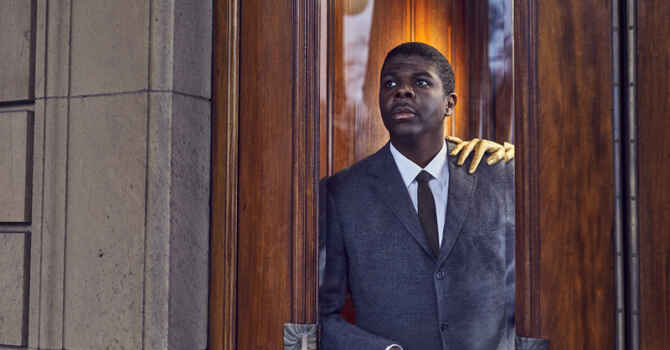 Black man with gold hand resting on shoulder