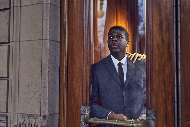 Black man with gold hand resting on shoulder